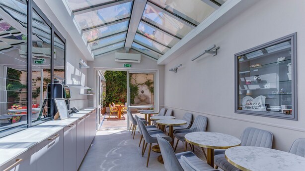 Un caffè moderno con soffitto in vetro, posti a sedere interni e una vetrina espositiva.