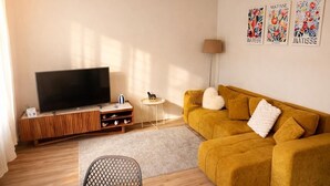 Un soggiorno con divano, televisore e opere d'arte alle pareti.