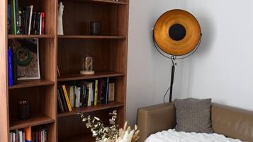 A modern living room with a large wooden bookshelf, a round floor lamp, and a beige sofa.