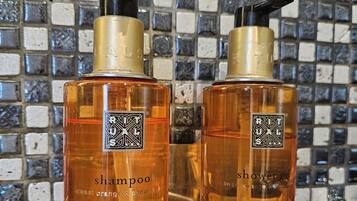 Two bottles of Ritual of Meer shampoo and shower gel against a mosaic tile wall.