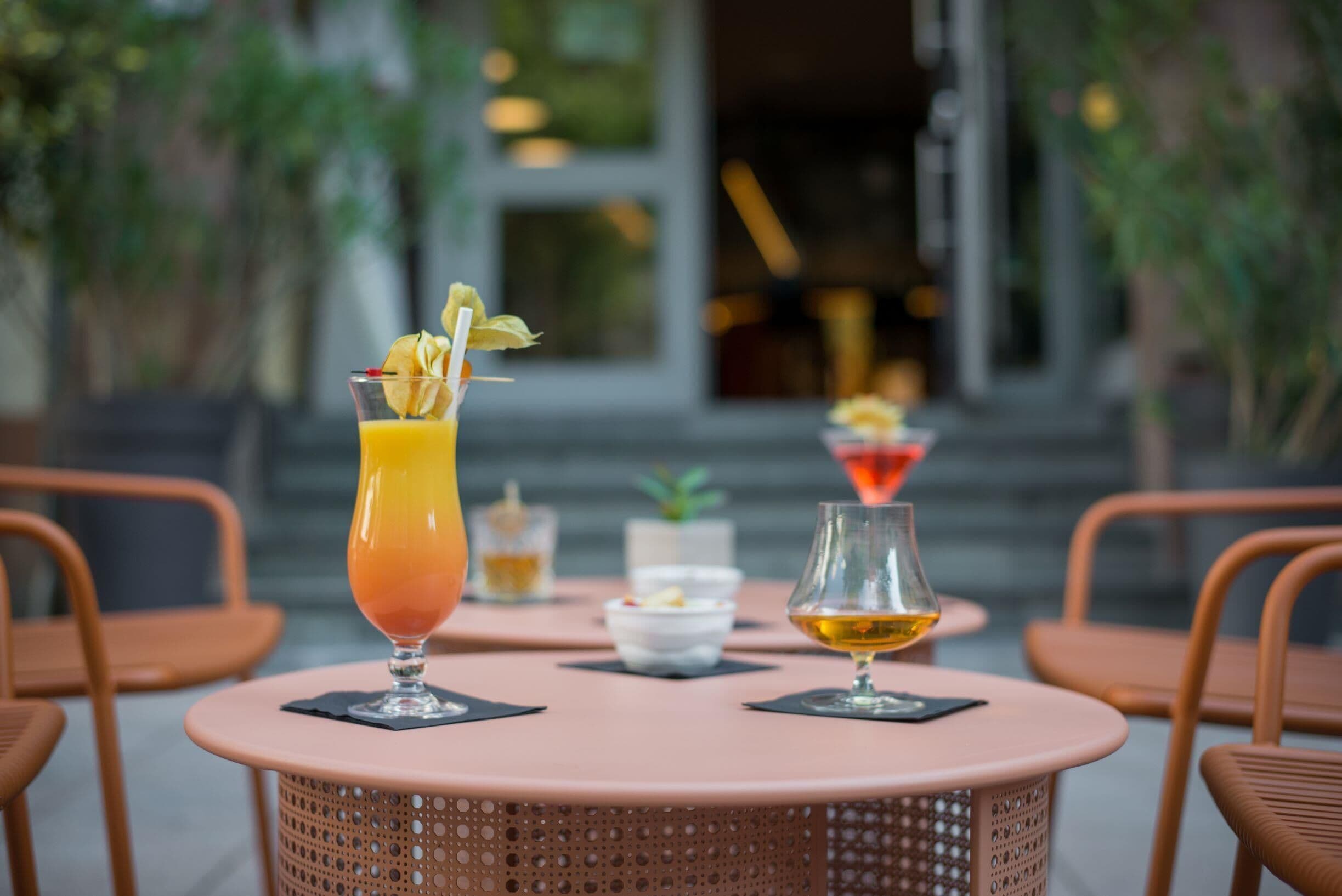 Een tafel met drankjes en een kleine schaal fruit, omringd door rieten stoelen.
