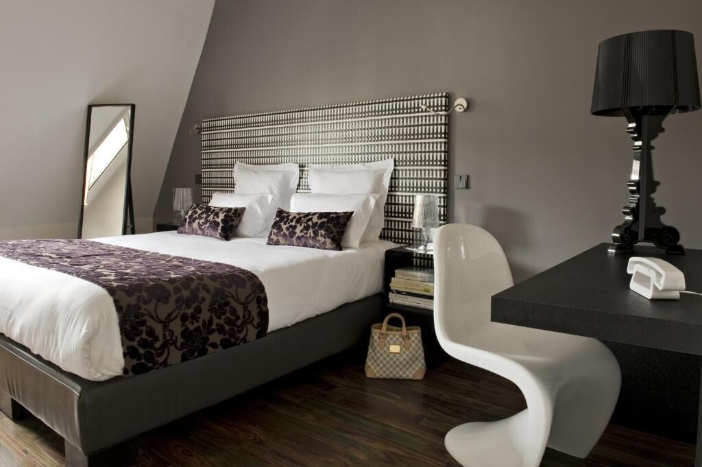 Une chambre d’hôtel moderne équipée d’un lit, de tables de chevet, d’un bureau avec une lampe et d’une chaise.