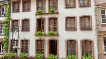 Un hôtel à l’architecture européenne traditionnelle, doté de nombreuses fenêtres et d’un espace salon au rez-de-chaussée avec des chaises d’extérieur.