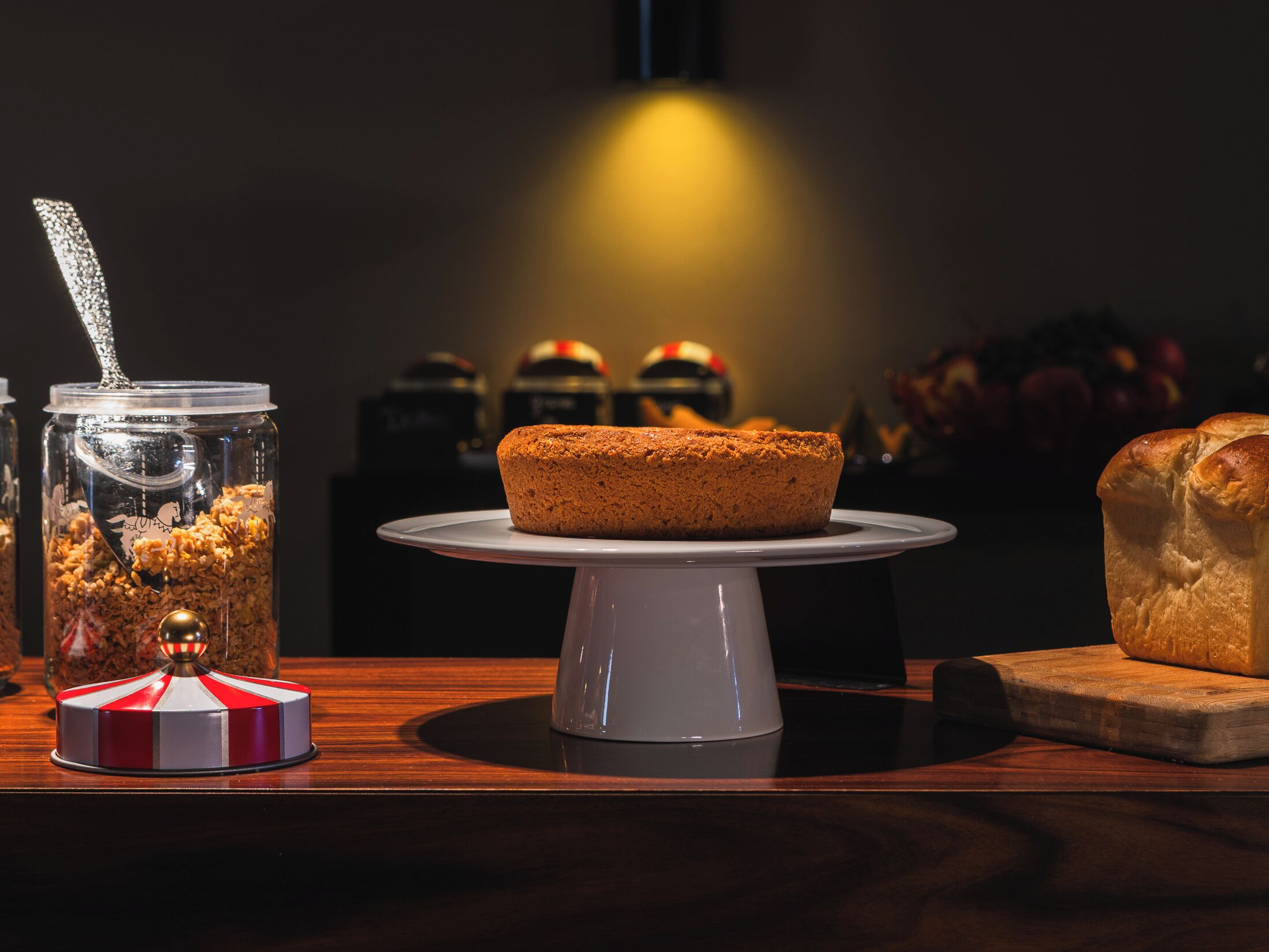 A cake on a white cake stand with a dark background.