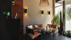 A modern interior with wicker chairs, a dark reception desk, and a large window with natural light. - L'Hôtel - Face au Château - Boutique Hôtel et Séminaires (Nantes)