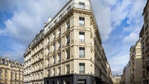 A corner building with a classic architectural style, featuring multiple balconies and a prominent entrance. - Le 46 Hotel (Paris)