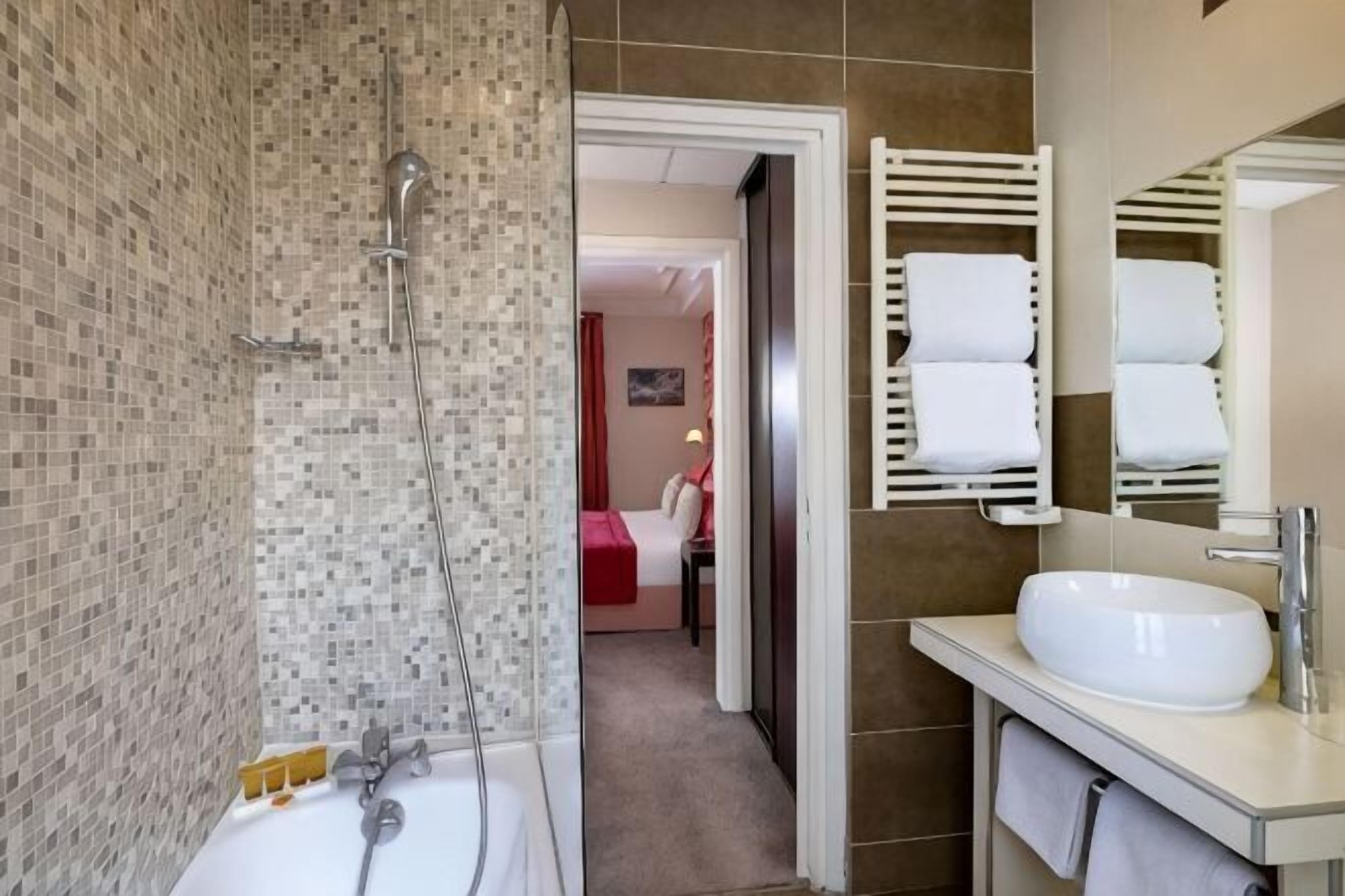 Un bagno con doccia, lavandino e porta asciugamani.