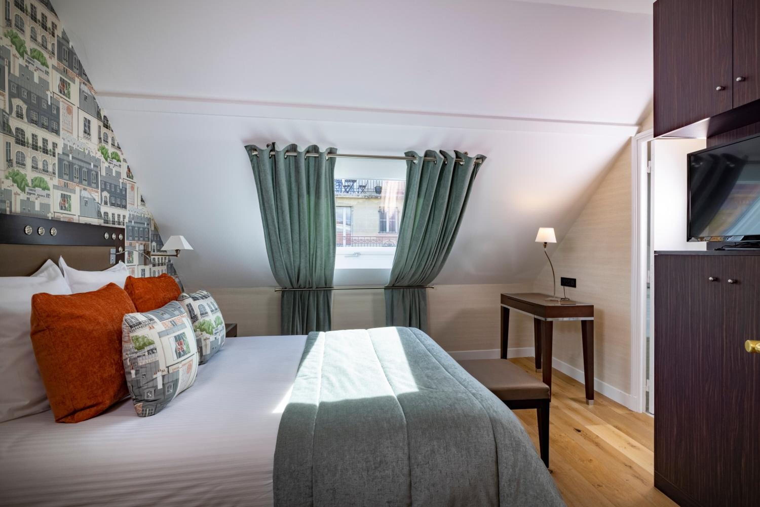 Ein Hotelzimmer mit Bett, Schreibtisch, Fernseher und einem Fenster mit Vorhängen.
