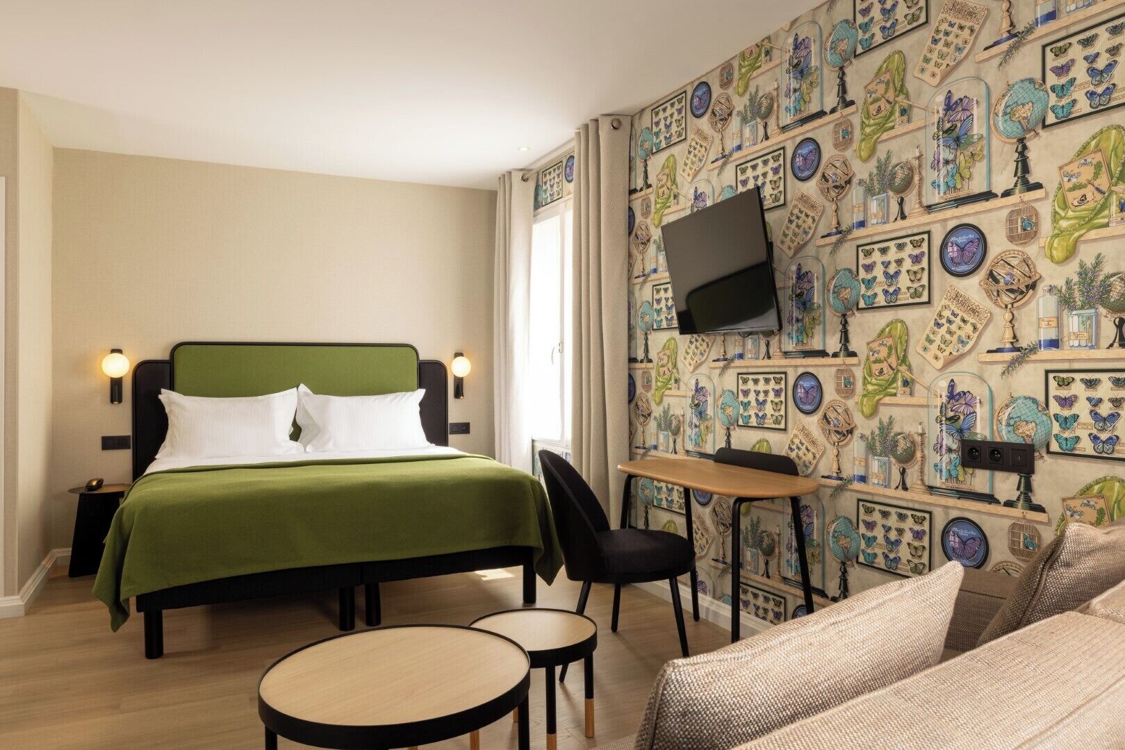 A hotel room with a bed, a desk, a TV, and a patterned wall.