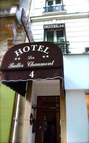 Un cartel de hotel con el nombre "HOTEL Des Buttes Chaumont" y el número 4, indicando la dirección del edificio.
