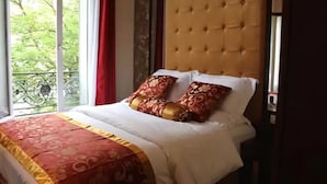 Un dormitorio con un ventanal grande, un cabecero capitonado y una colcha estampada.