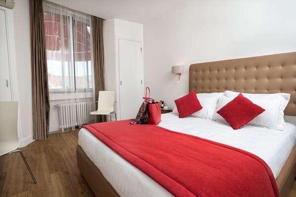 Ein Hotelzimmer mit einem großen Bett, einer roten Decke und einer roten Handtasche auf dem Bett.