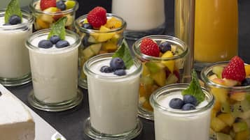 A variety of yogurt parfaits in glass jars, each topped with fresh fruits and mint leaves.