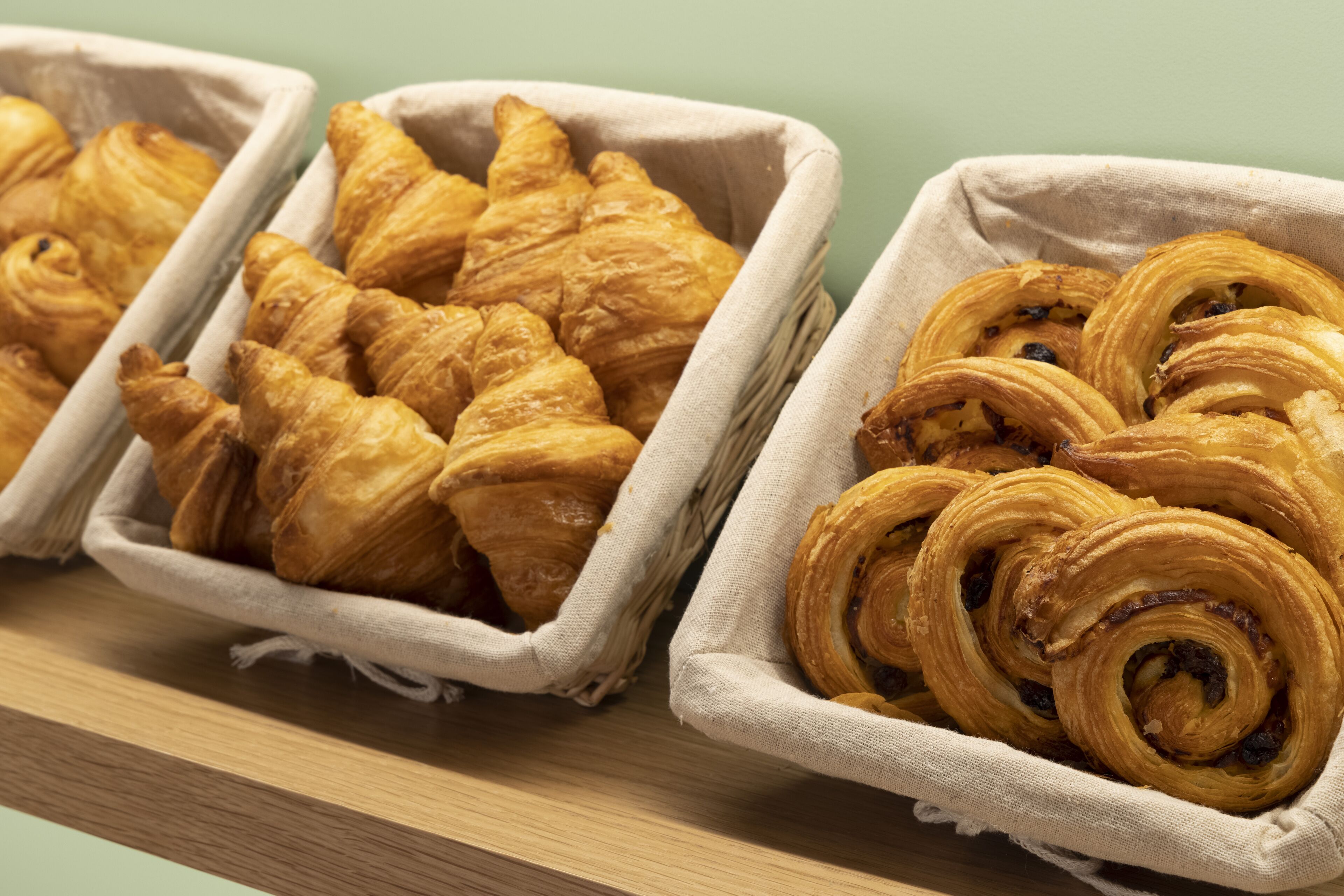 Two baskets of pastries on a wooden shelf.
