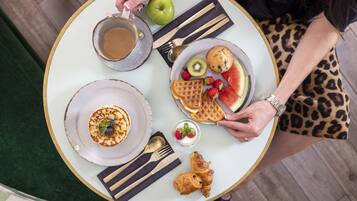 Ein Tisch mit Frühstücksangeboten, darunter Waffeln, ein Croissant und eine Tasse Kaffee.
