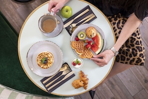 A table with breakfast items including waffles, a croissant, and a cup of coffee.