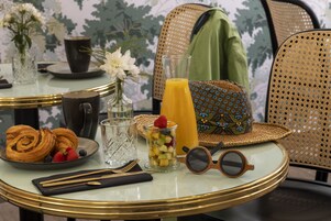 A breakfast table with croissants, fruit, juice, and sunglasses.