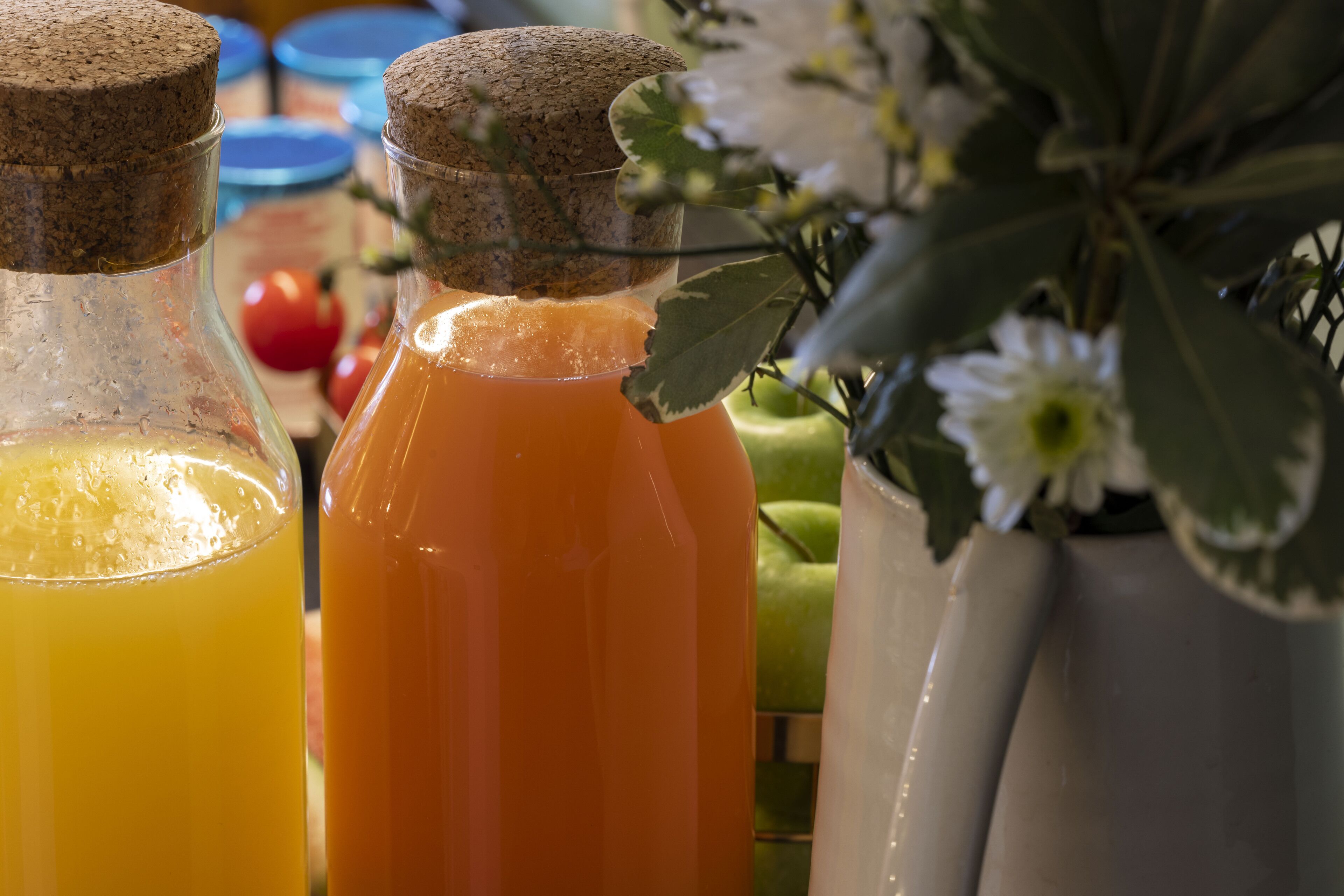 Two glass bottles with cork stoppers, one containing a yellow liquid and the other an orange liquid.