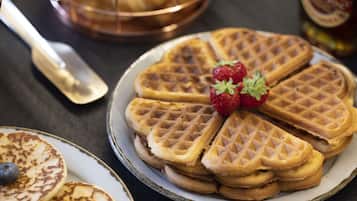Uma pilha de waffles com morangos e mirtilos.