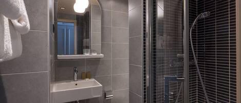 A modern bathroom with a glass-enclosed shower, a white sink, and a mirror above it.