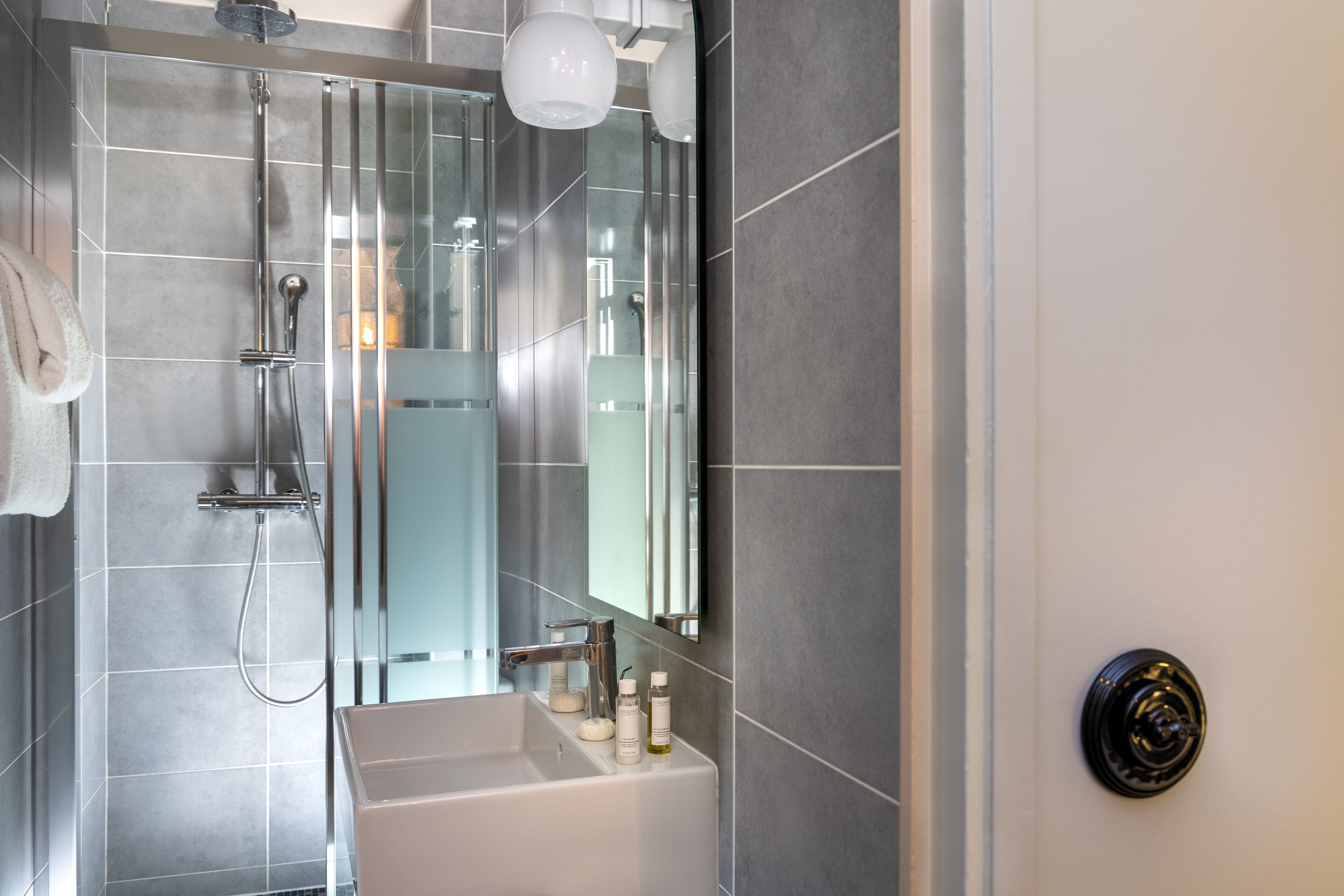 Un baño moderno con ducha de vidrio, un lavabo blanco y un espejo.