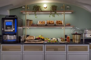 A breakfast bar with a coffee machine, bread, fruits, and various breakfast items.