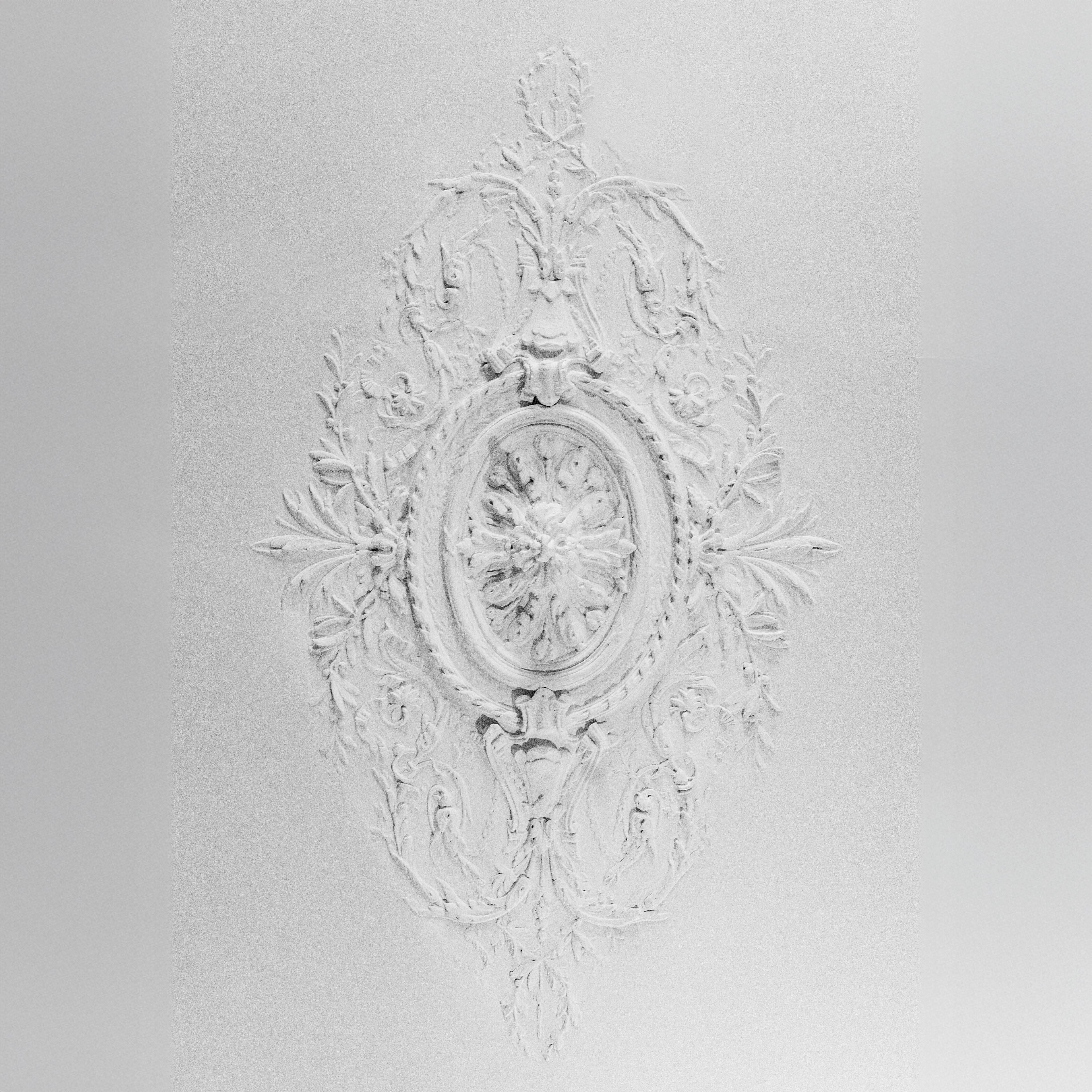 Un motif blanc, orné et en relief, sur un mur.