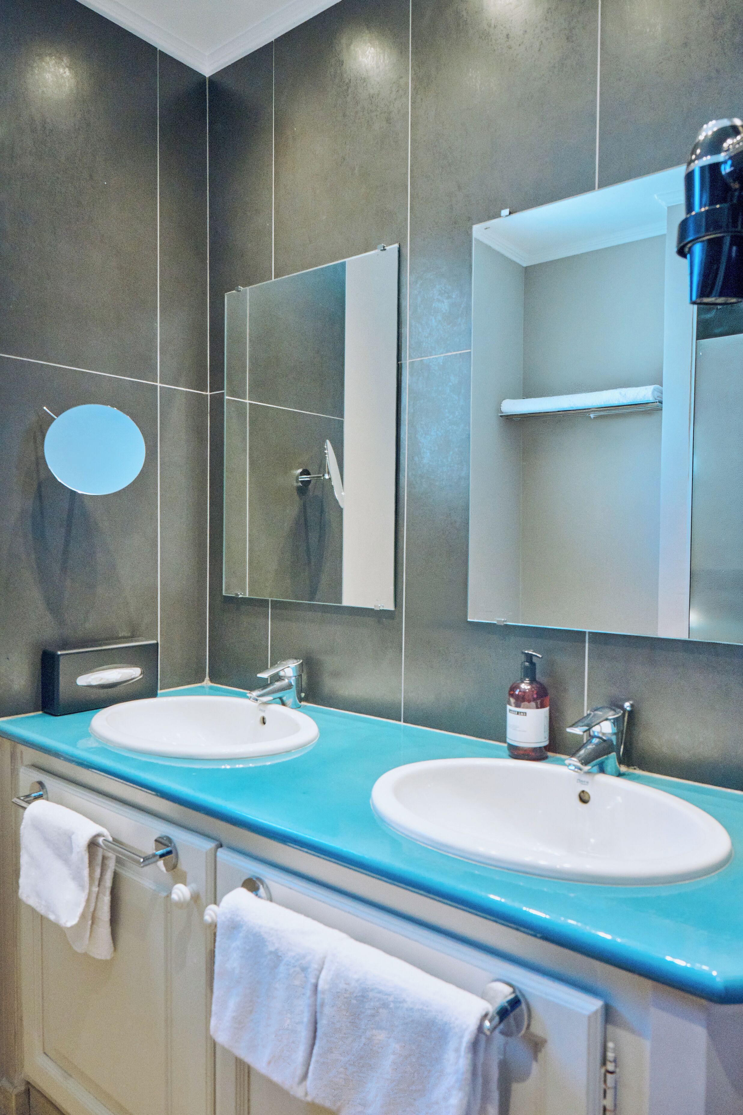 A bathroom with two sinks, a mirror, and a towel rack.