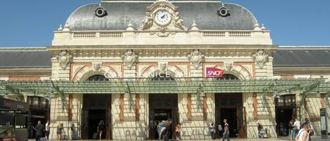 A historic building with a clock tower, ornate facade, and a sign reading "GARE DE NICE VILLE".