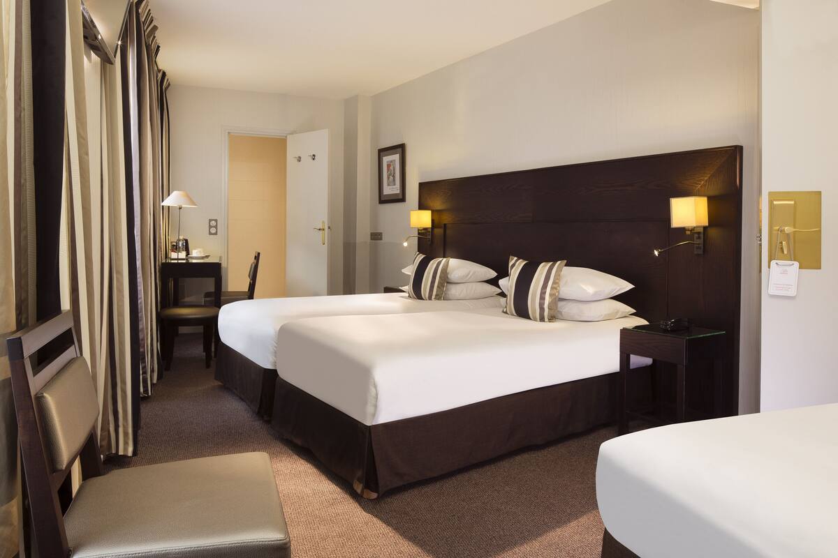 Une chambre d’hôtel avec deux lits, un bureau et une chaise.