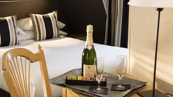 A hotel room with a bed, a bottle of champagne, two glasses, and a tray with macarons.