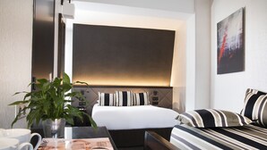 A hotel room with a bed, bedside table, and a chair. There is a potted plant on the table and a magazine on it. - Hotel Albert 1er Paris Lafayette (Paris)