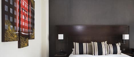 A hotel room with a large bed, two bedside lamps, a nightstand, and a chair.