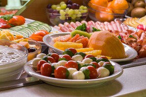 A buffet with various food items including fruits, cheeses, and vegetables.