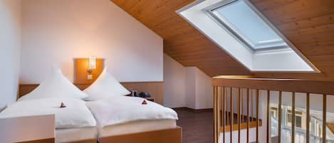 Un dormitorio con tragaluz, techo de madera y una cama con ropa de cama blanca.