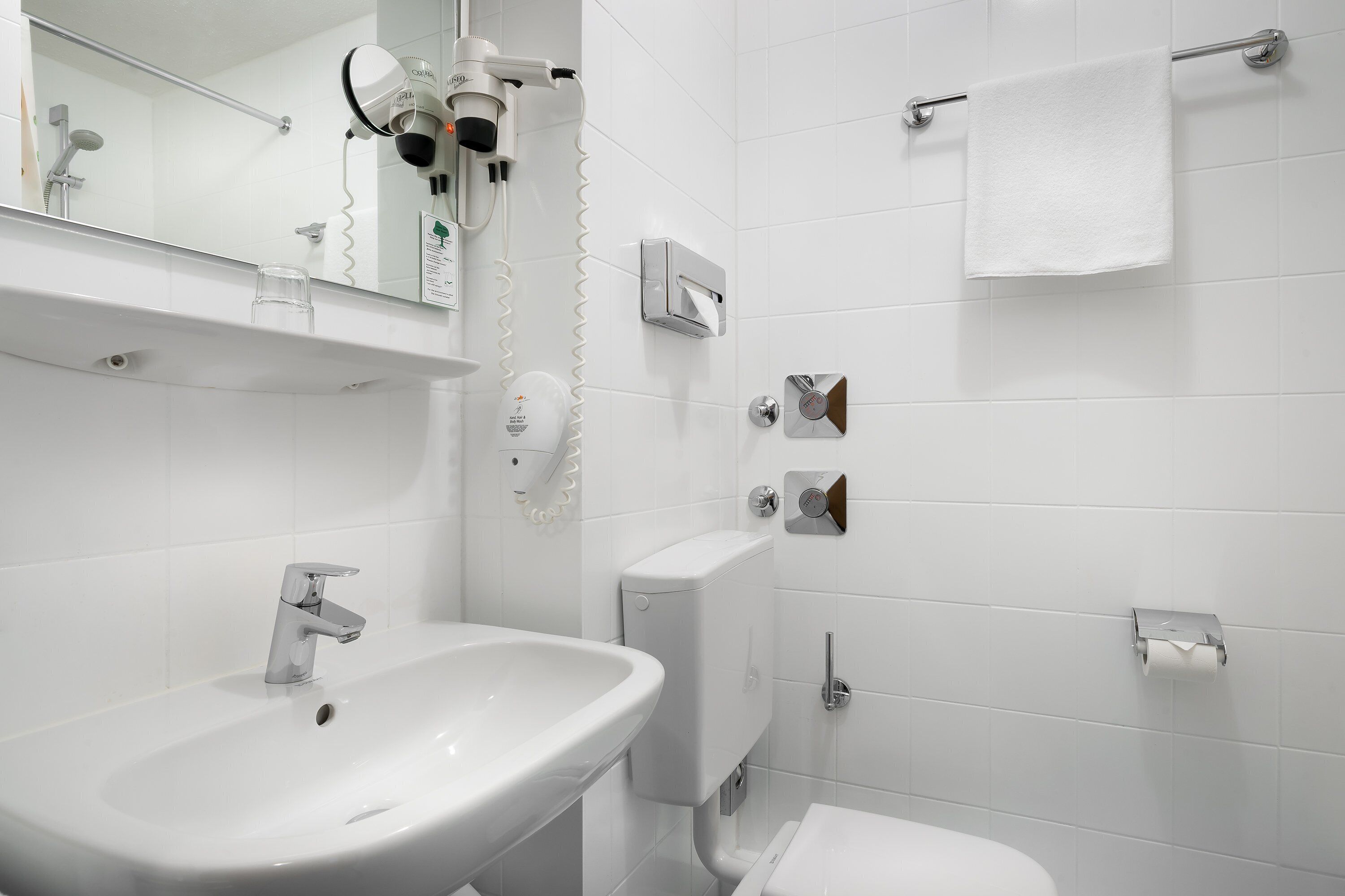 A modern bathroom with a white sink, a toilet, and a towel rack.