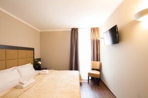 Una habitación de hotel con una cama, una silla, un televisor y cortinas.