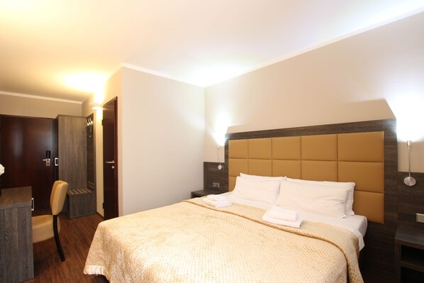 Una habitación de hotel con una cama, mesitas de noche, un escritorio y una silla.