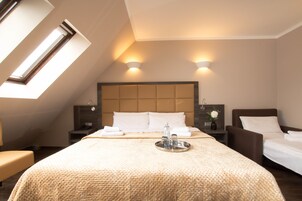 A hotel room with a large bed, two bedside tables, a nightstand, a window with a view, and a skylight.