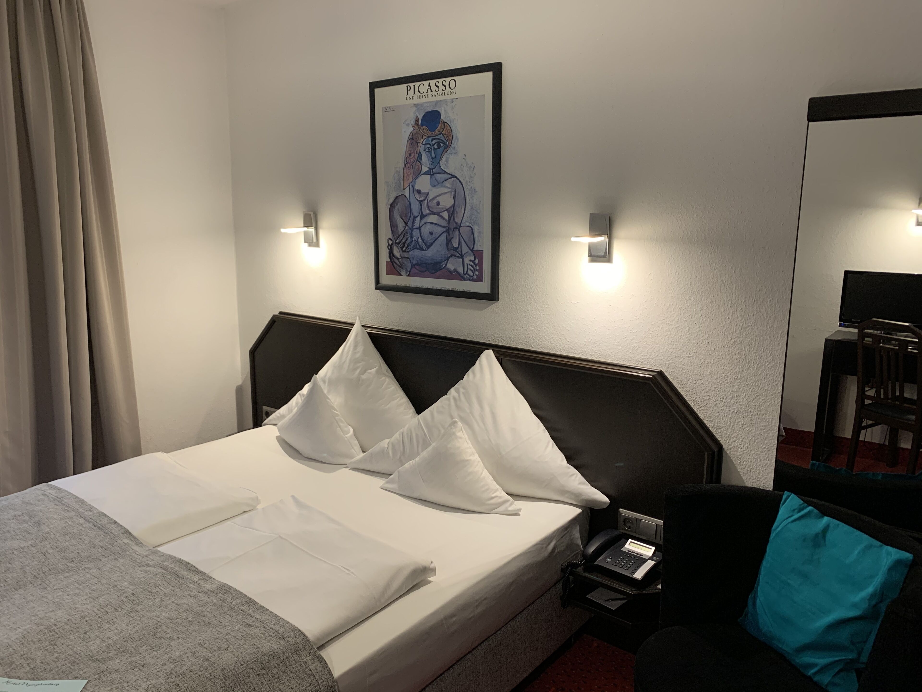 Ein Hotelzimmer mit Bett, Nachttisch, Telefon und einem Bild an der Wand.