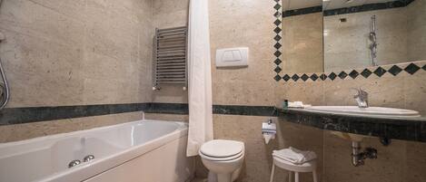 A bathroom with a bathtub, toilet, sink, and a mirror.