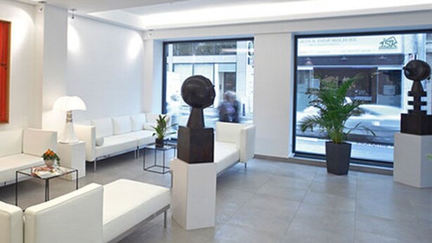 Eine moderne, geräumige Lobby mit weißen Sofas, einem Couchtisch und topfpflanzten Pflanzen.