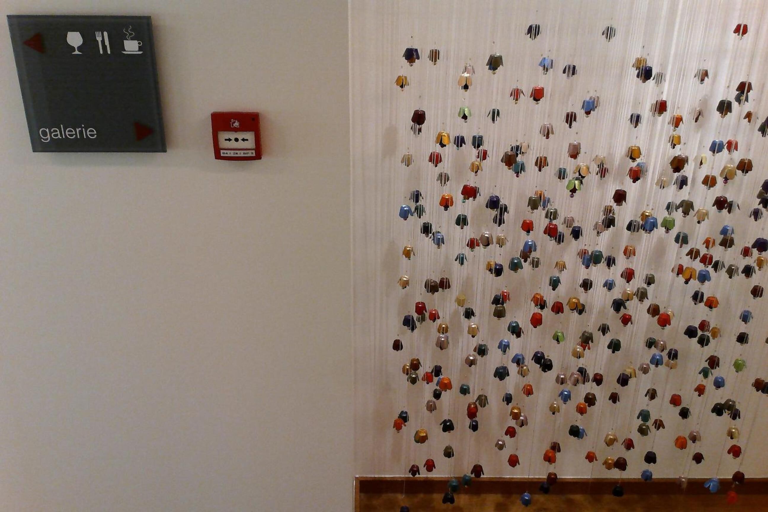 Een muur met een bordje met de tekst 'galerie' en een rookmelder.