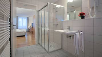 Une salle de bain moderne avec une douche à parois de verre, un lavabo et un miroir.