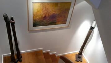 Una escalera con peldaños de madera y un cuadro abstracto enmarcado en la pared.