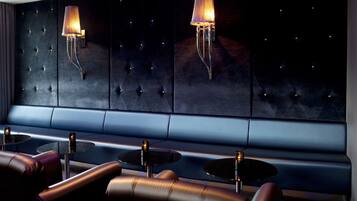 Un salon moderne avec un mur capitonné, des sièges en cuir et des tables rondes.