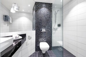 A modern bathroom with a black mosaic shower wall, a white toilet, and a glass-enclosed shower area.