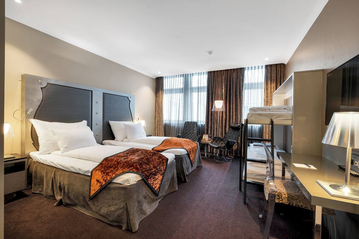 Ein Hotelzimmer mit zwei Betten, einem Schreibtisch, einem Stuhl und einem Fernseher.
