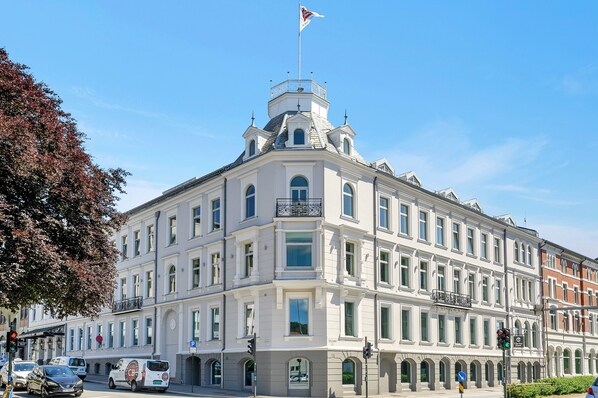 A historic building with a prominent corner turret, large windows, and a flag on top.