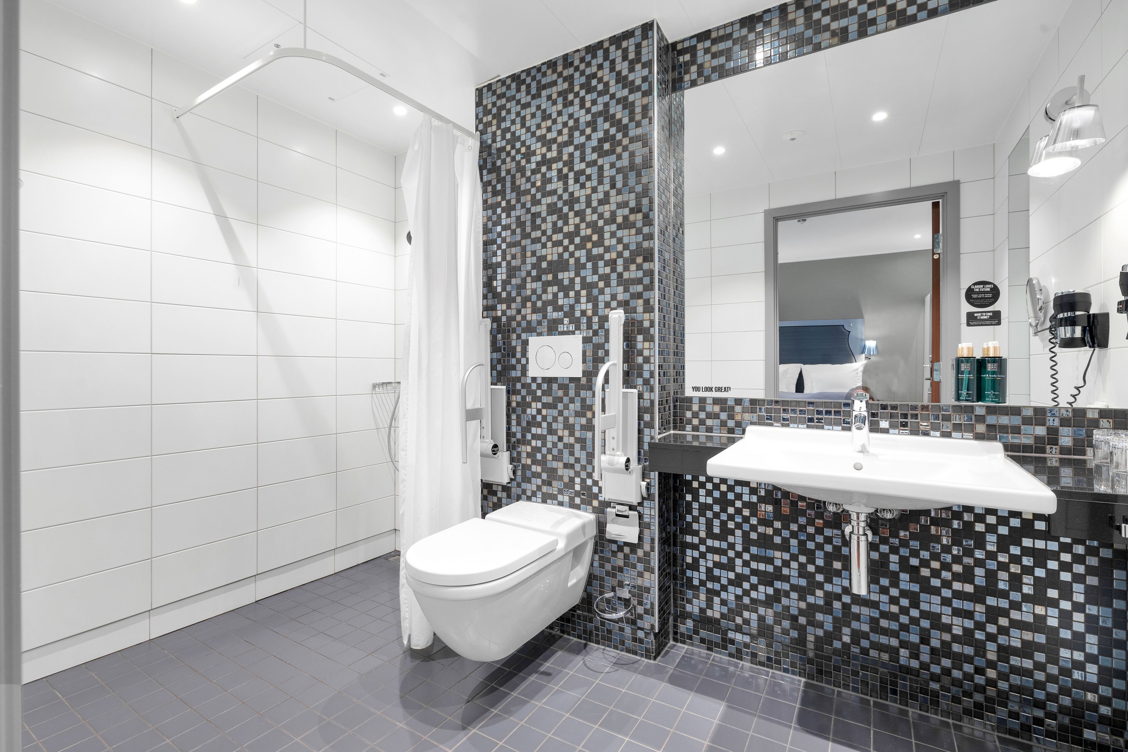 A modern bathroom with a white toilet, a shower area, and a sink with a tiled backsplash.